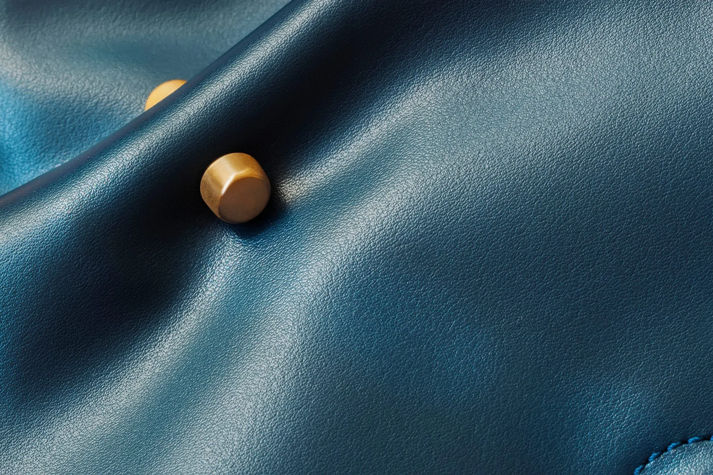 Close-up of blue leather with a brass rivet.